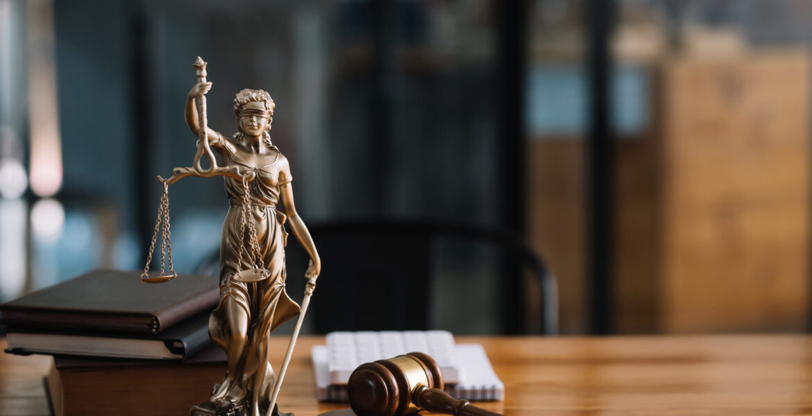 Lady Justice statuette on a desk with javel and books.