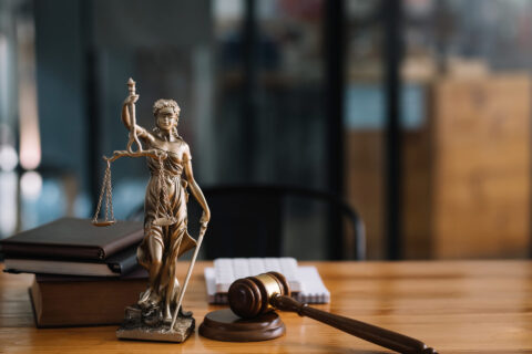 Lady Justice statuette on a desk with javel and books.