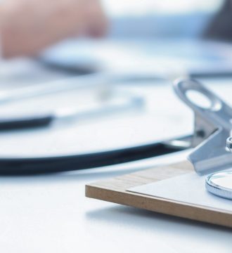 Stethoscope and clip board on doctor workplace close up