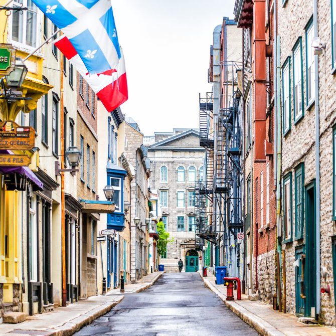 Quebec City, Canada - May 30, 2017: Empty narrow European street in upper old town called Rue Garneau with flags and wet road